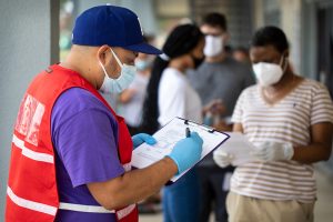 Community outreach specialist Rogelio Bucio collects patient information as they wait in line at a walk up Covid-19 testing site on June 27, in Dallas, Texas.
