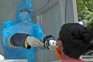 A health worker wearing Personal Protective Equipment (PPE) gear collects a swab sample of a boy at a government free testing centre in Hyderabad, India on July 17.