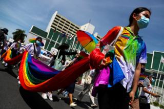 Mitglieder einer Jugendstolz-Studentengruppe tragen ein langes Stück Stoff mit Regenbogenmuster