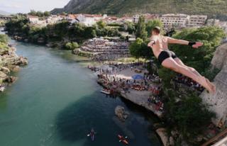 Ein Mann, der aus einer Höhe in den Fluss Neretva in Mostar ins Wasser taucht